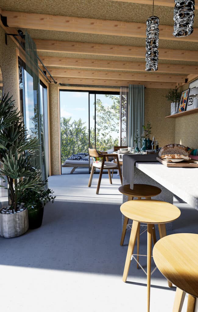 Intérieur studio de jardin charpente bois apparente îlot tabourets plantes baie vitrée ouverte sur jardin