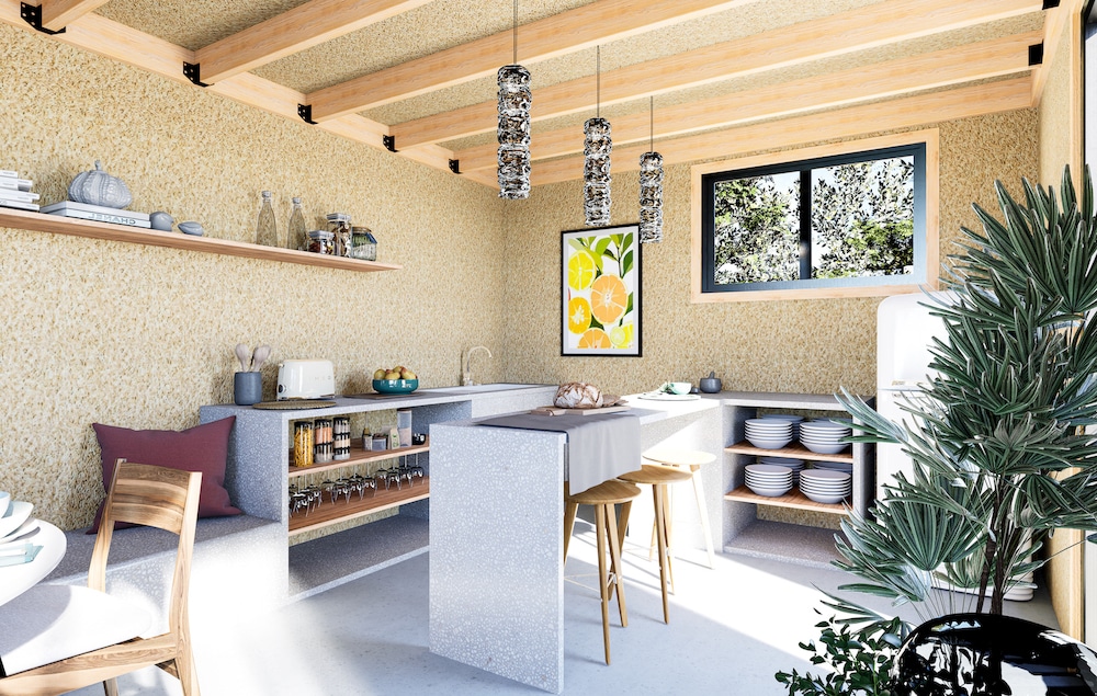 Intérieur studio de jardin coin cuisine îlot central tabourets bois charpente apparente fenêtre sur jardin