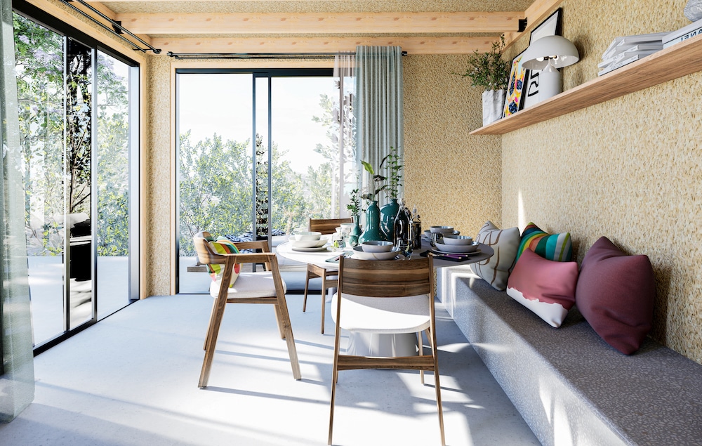 Intérieur studio de jardin coin repas banquette coussins table bois baie vitrée ouverte sur terrasse
