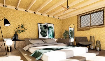 Chambre douillette dans un studio de jardin avec murs texturés jaunes et poutres en bois apparentes
