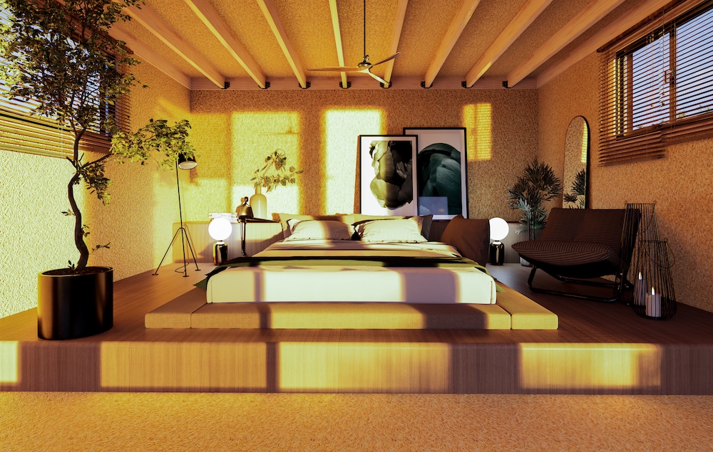 Intérieur de studio de jardin avec lit sur estrade, plafond solives bois et lumière du soir