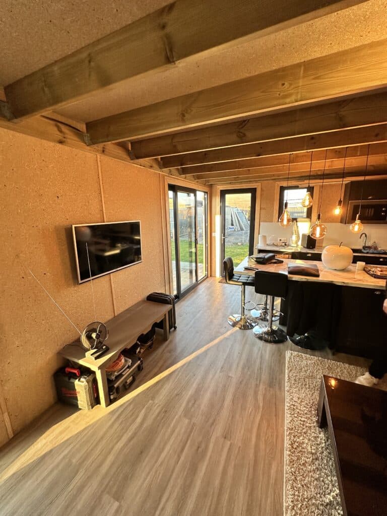 Intérieur d'un studio de jardin en bois avec cuisine, salon et vue sur jardin