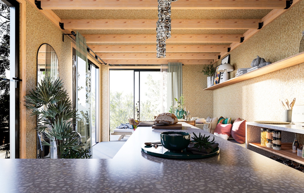 Intérieur de studio habitable avec plan de travail, poutres bois apparentes et baie vitrée sur jardin