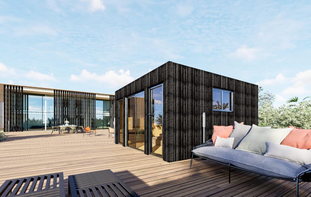 Studio de jardin habitable à bardage bois foncé avec grandes baies vitrées et terrasse en bois aménagée