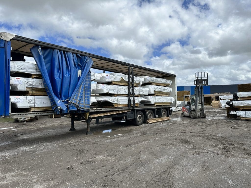 Chargement de palettes de bois emballees sur camion bache avec chariot elevateur en cour de scierie